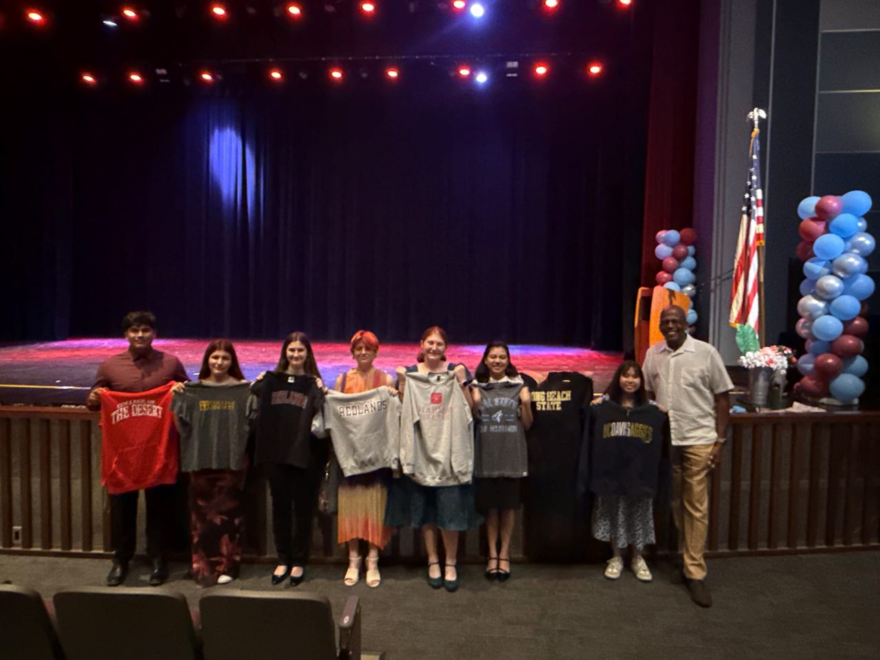 CSPcv scholars holding up their college shirts, with Program Director Dennis Reed